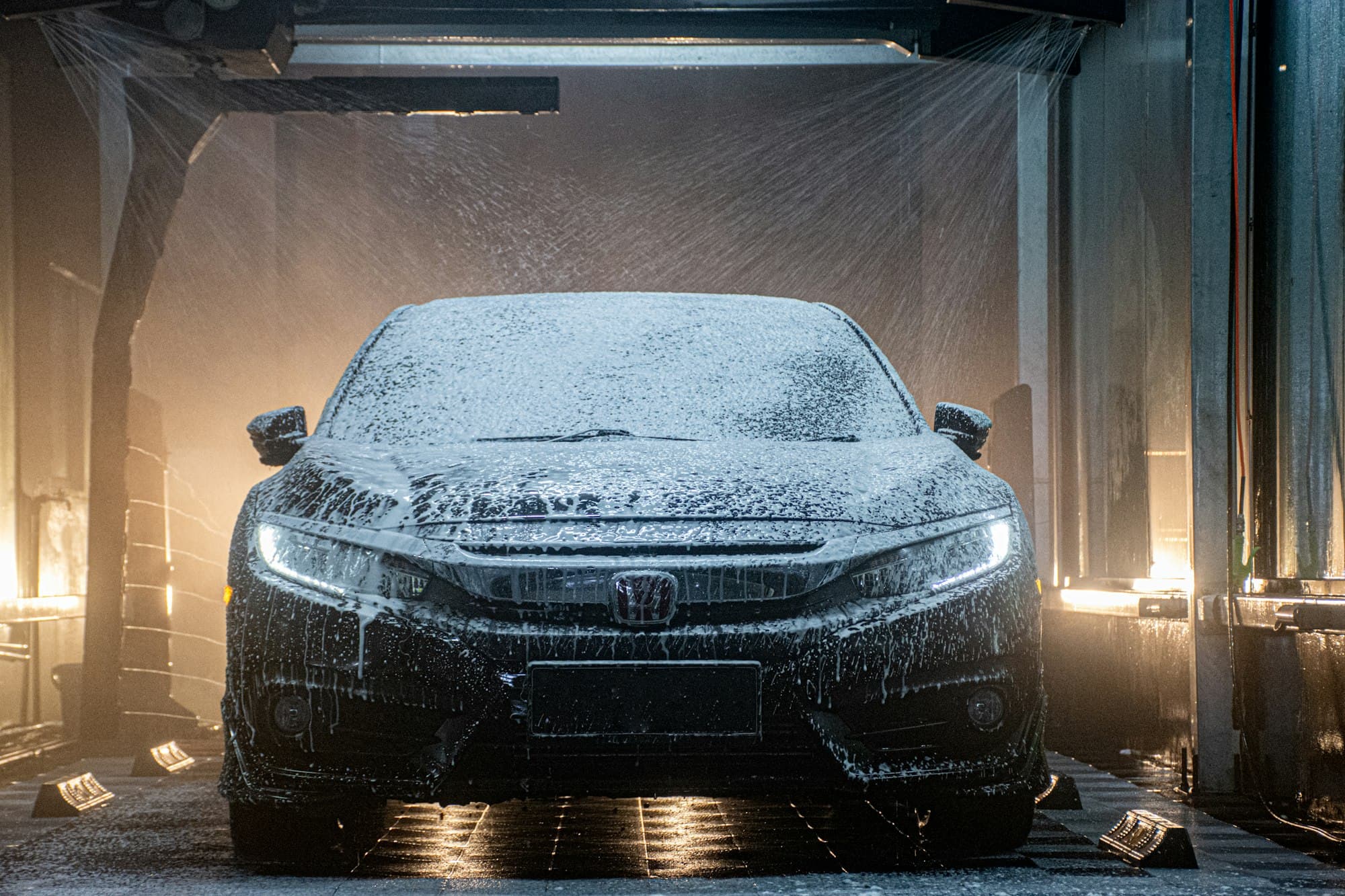 Car covered in snow foam in a wash bay