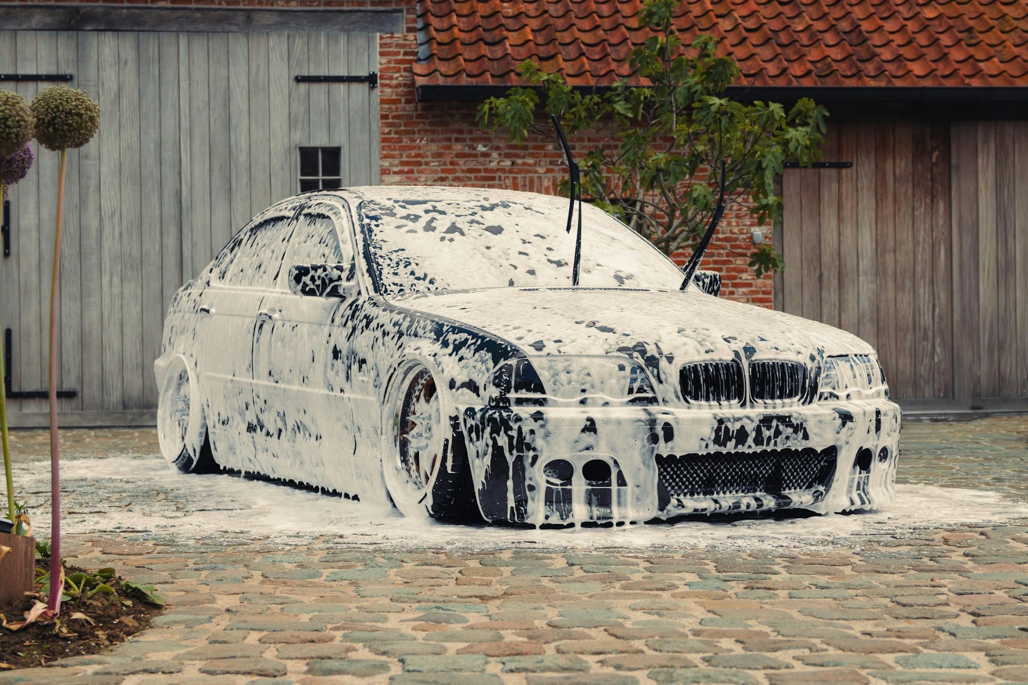 Car covered in snow foam outside a home