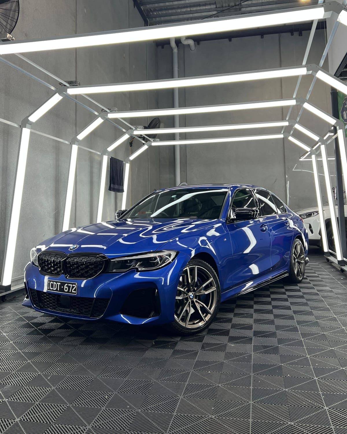 Blue BMW under the inspection light tunnel after paint correction