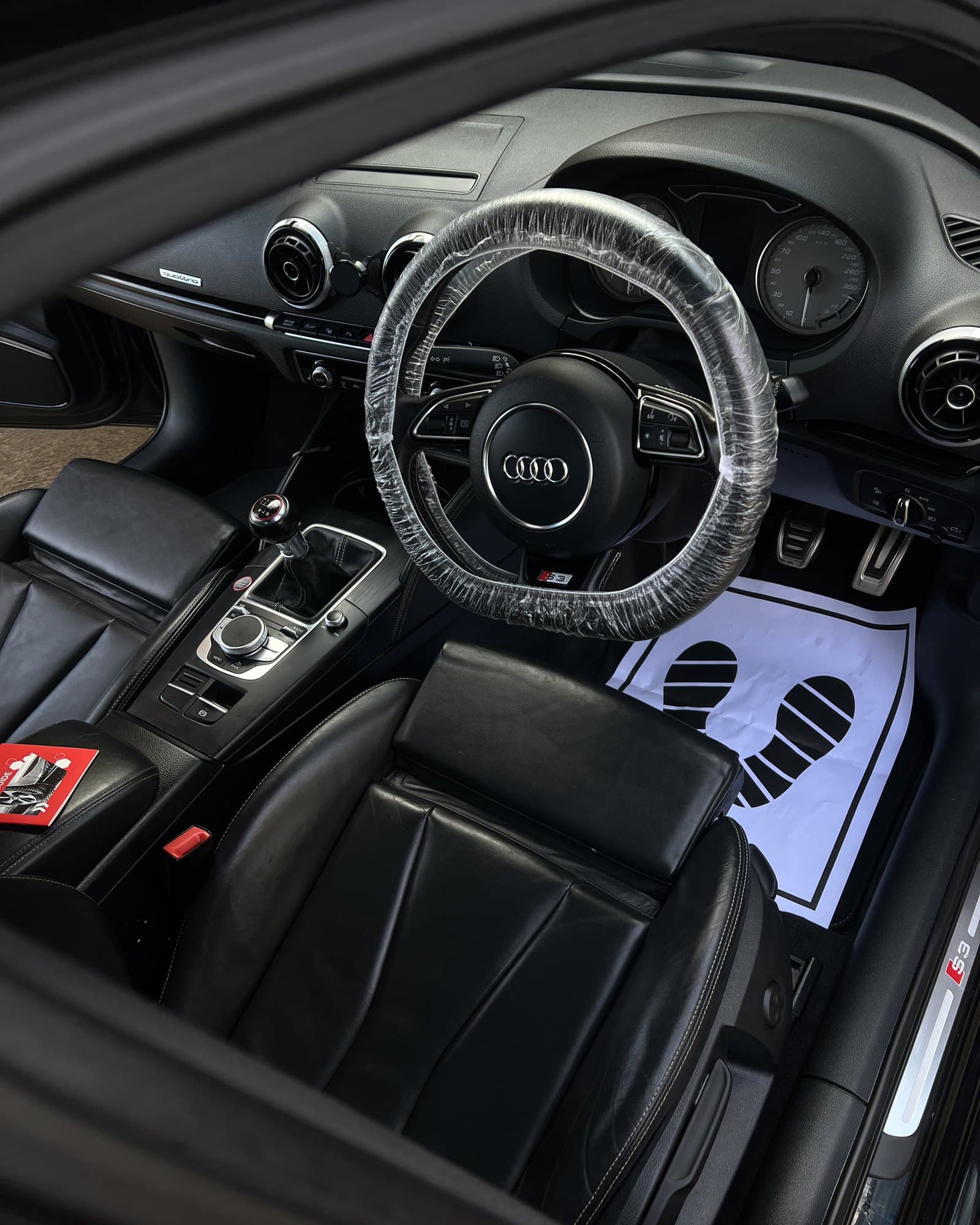 Car interior mid-detail with seat and steering wheel covers on