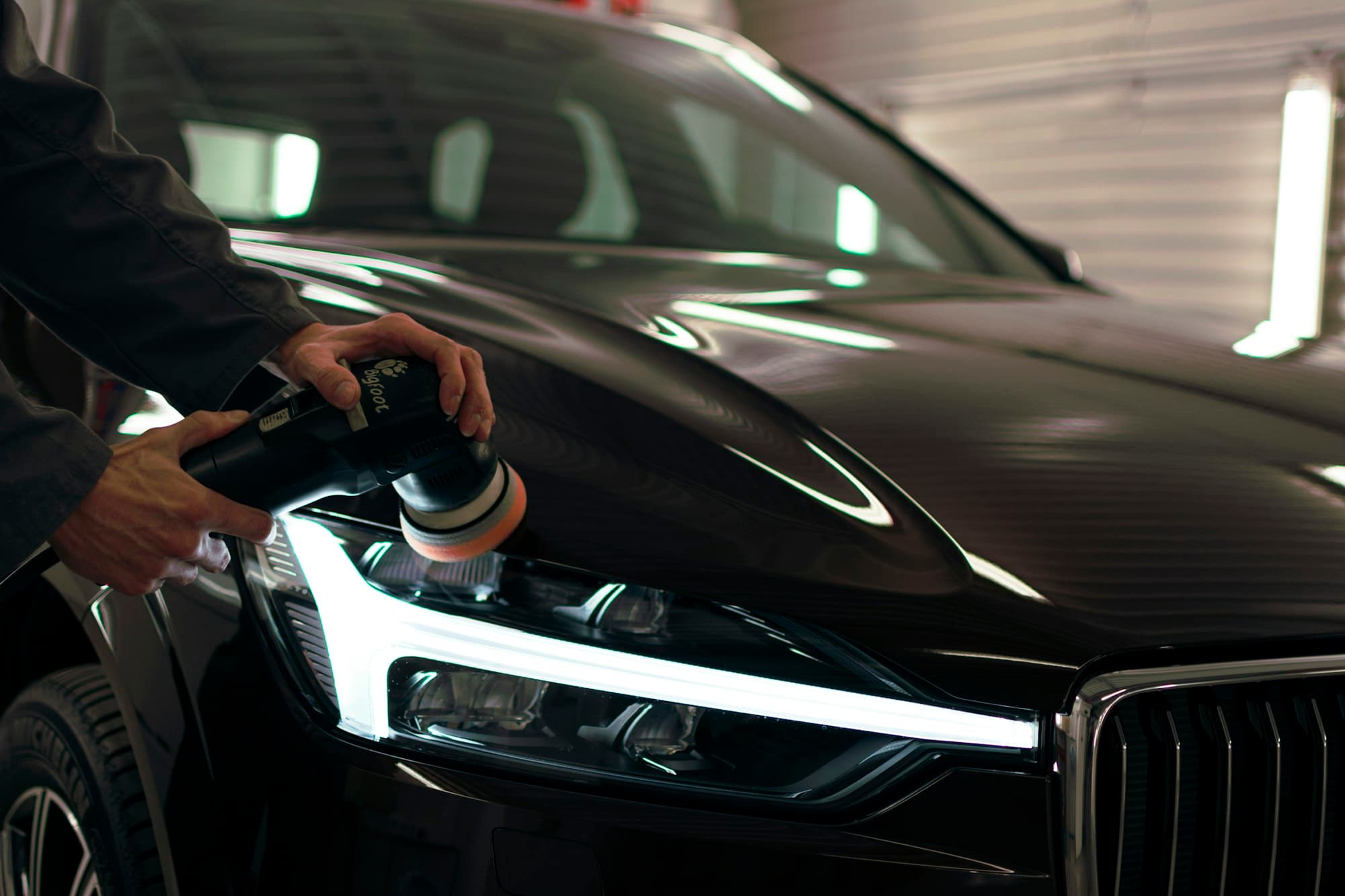 Headlight being polished with a machine polisher