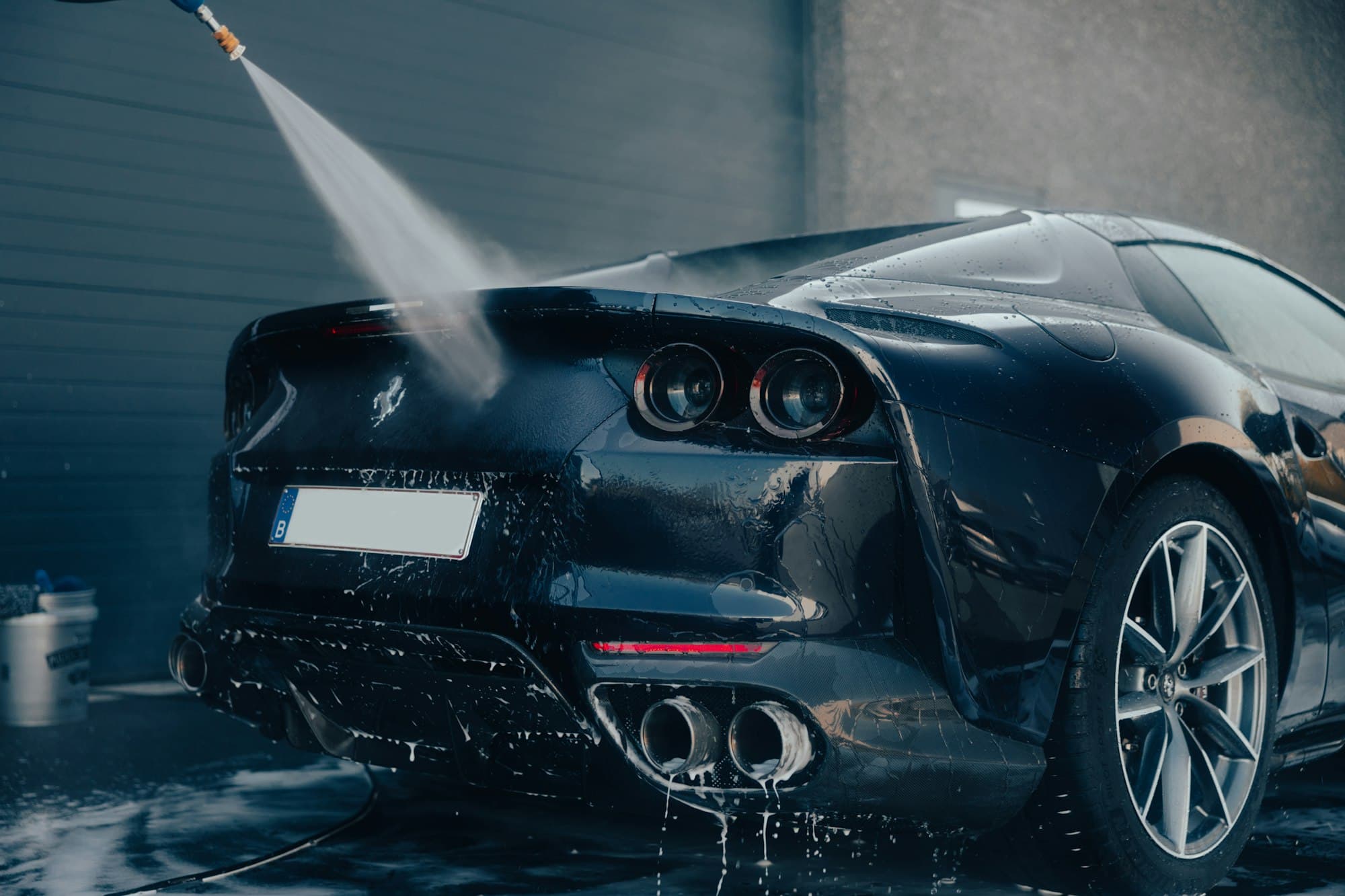 Black sports car being rinsed with a pressure washer