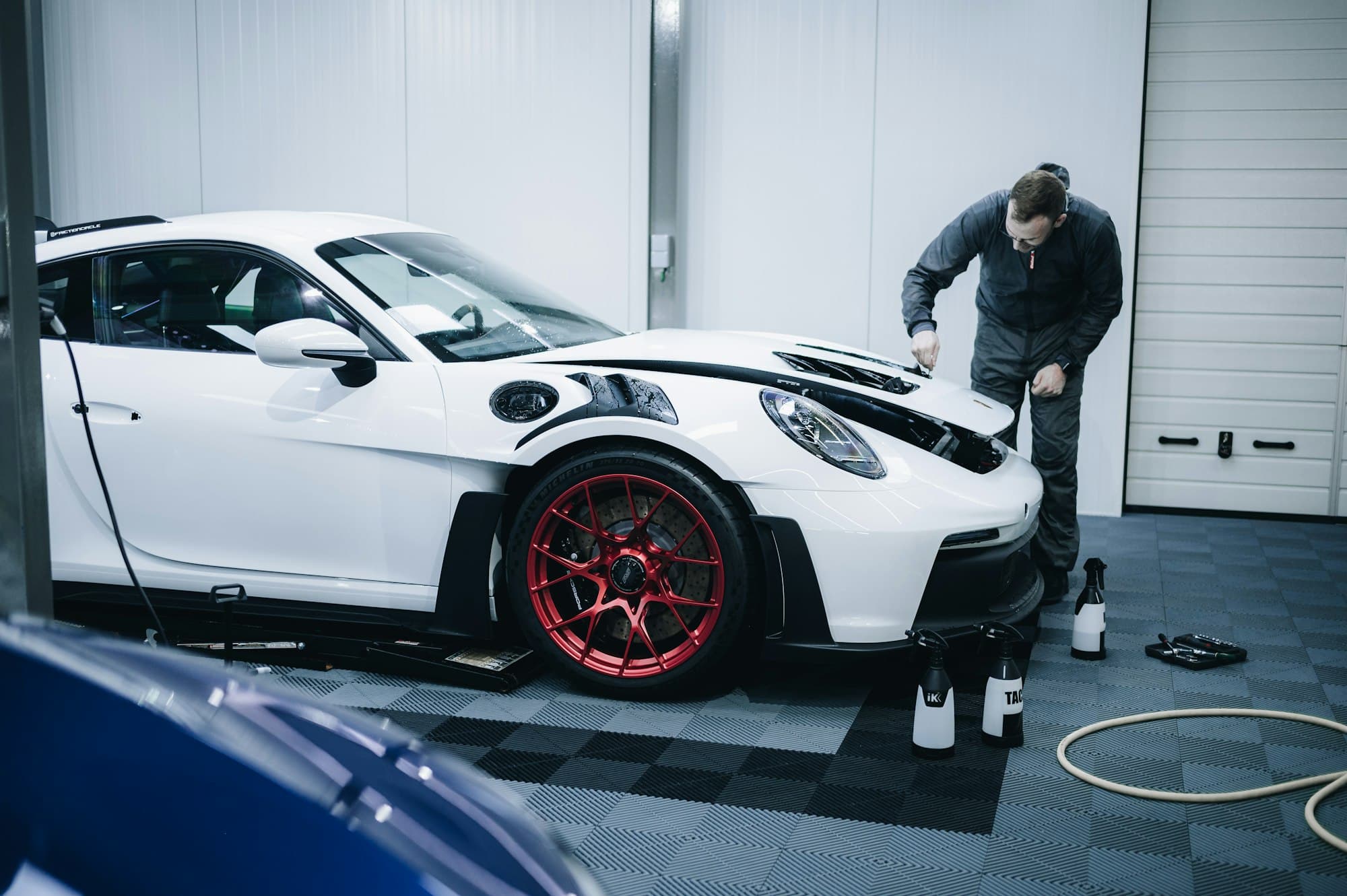 Detailer working on a white Porsche in a garage