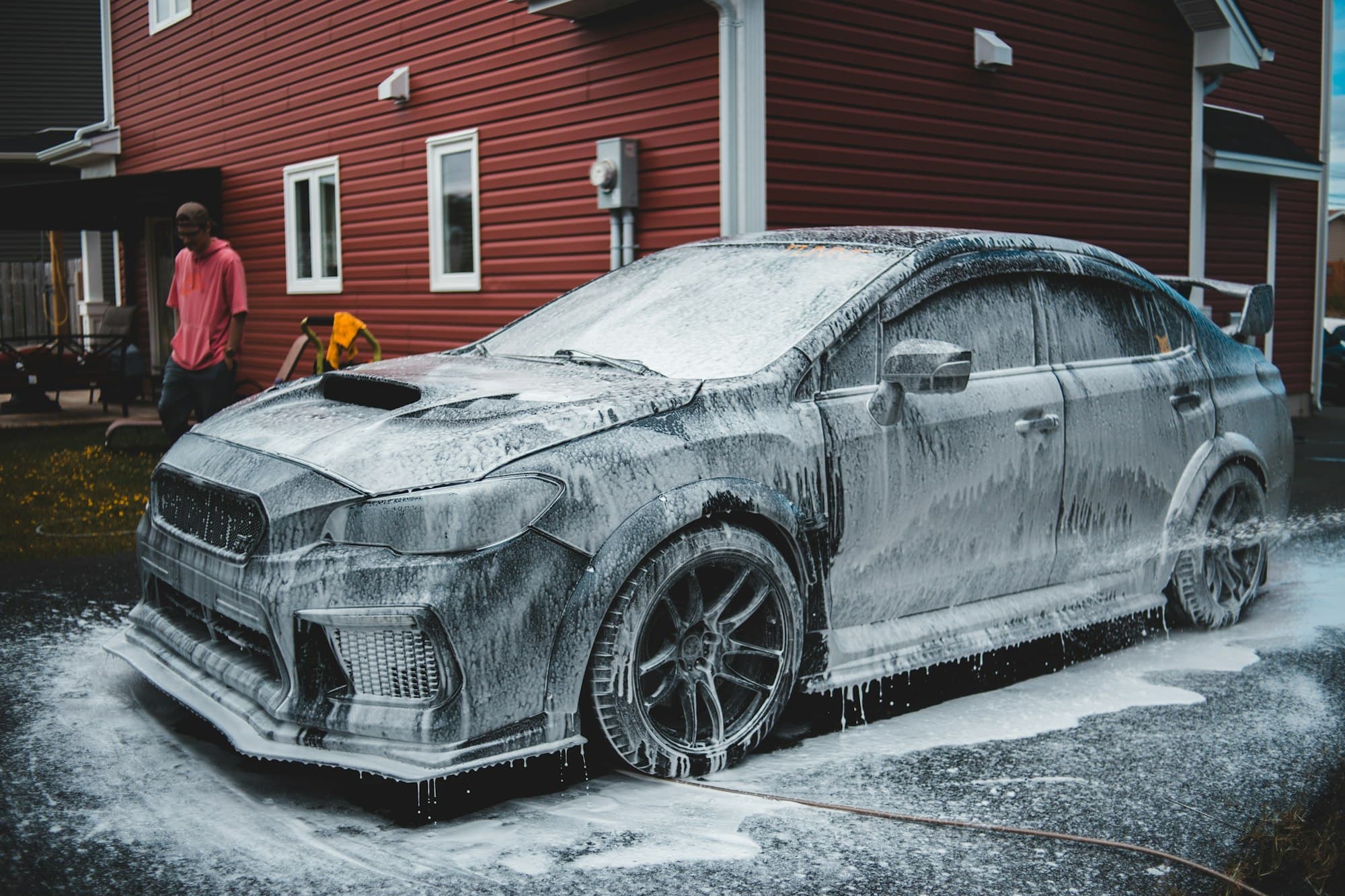 Car covered in snow foam outside a house