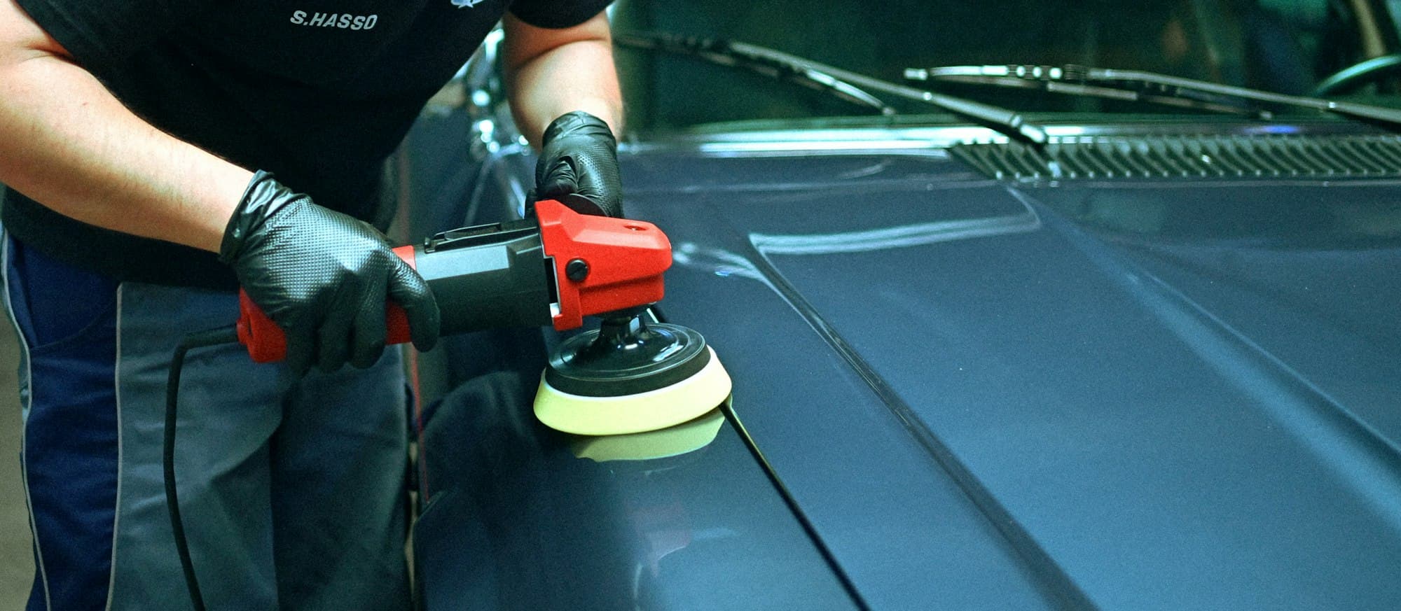 Orbital polisher on a dark blue car bonnet