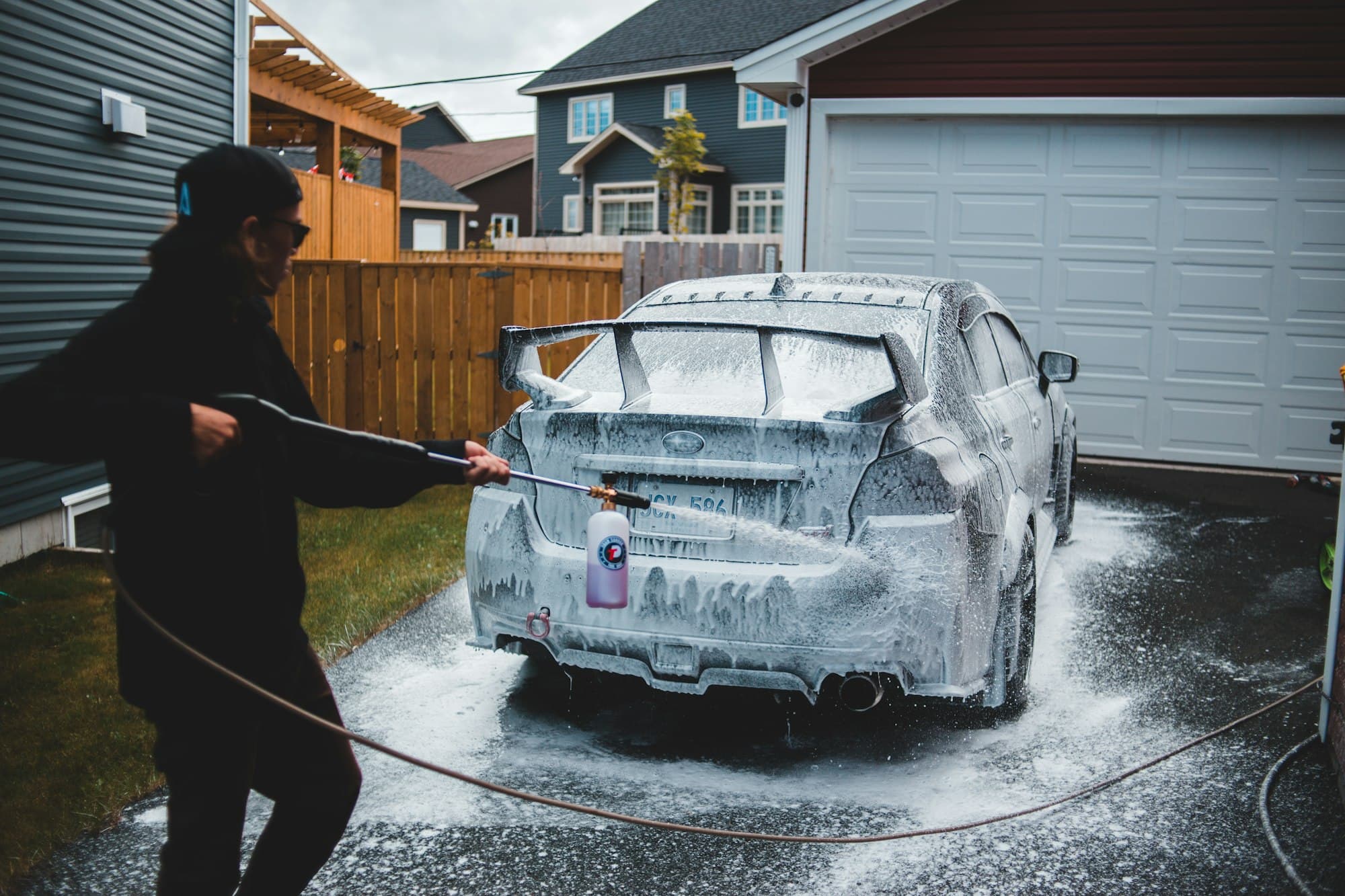 Car being pressure washed in a home driveway