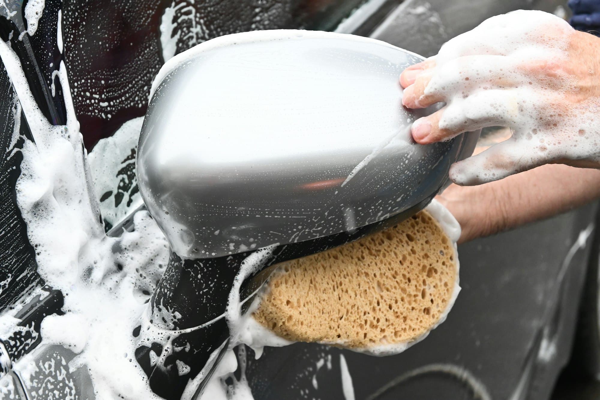 Car wing mirror being washed with a sponge