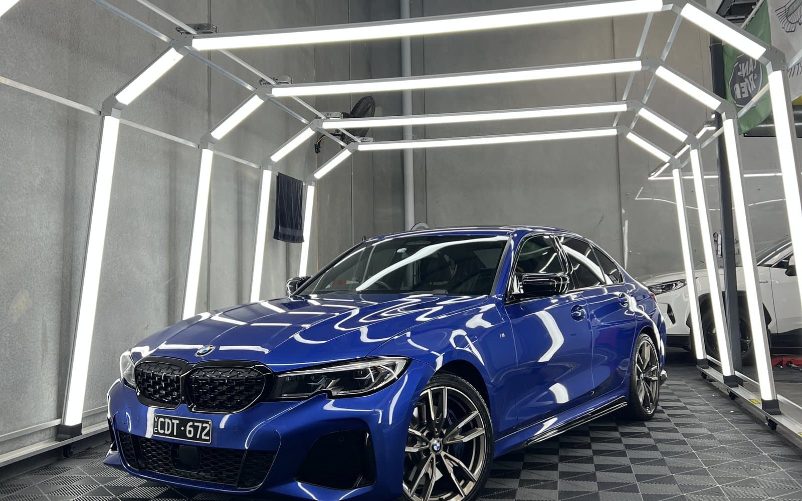 Blue BMW under inspection lights after a three-stage paint correction